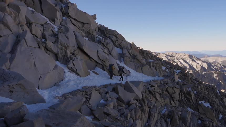 People hiking along a snow covered, rocky mountainside