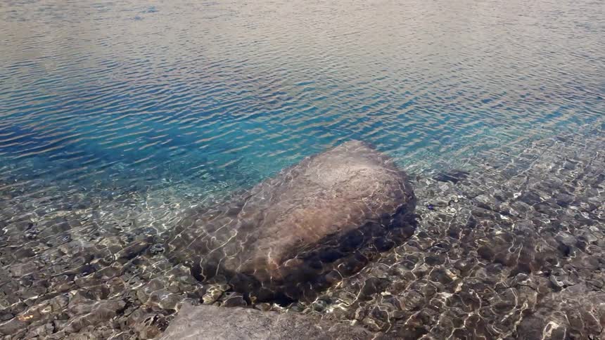 Shallow, clear water rippling over large and small rocks