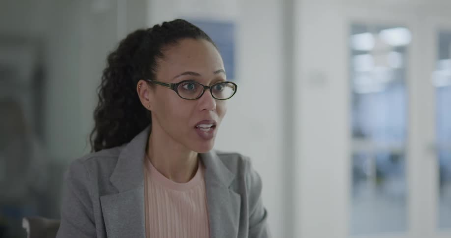 A woman in an office sits and talks to others