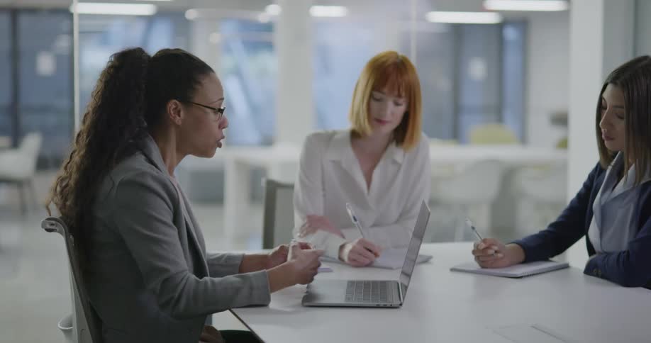 Three women brainstorm in a conference room together