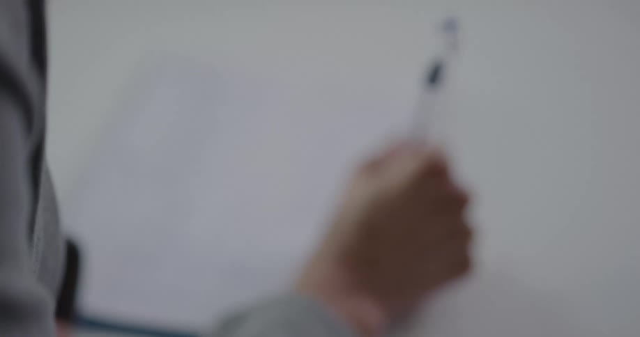 Businesswoman sitting at the table writes something on a piece of paper in the office
