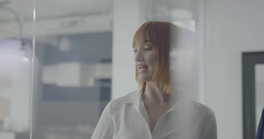 Two people in an office look at information on a board