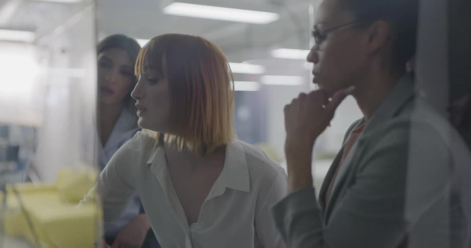 Women write on a white board and talk together in the office