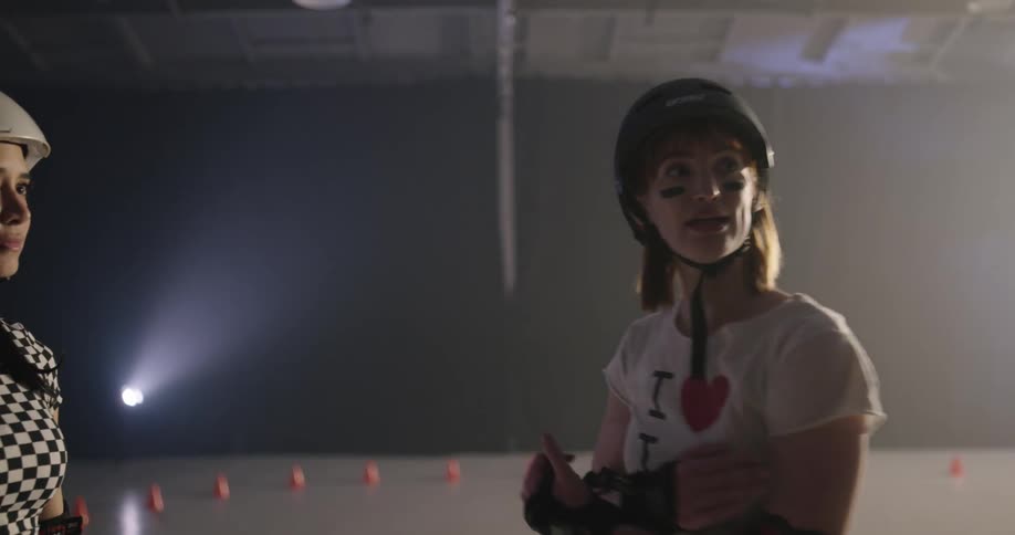 Four women in roller skates and protective gear stand together and talk