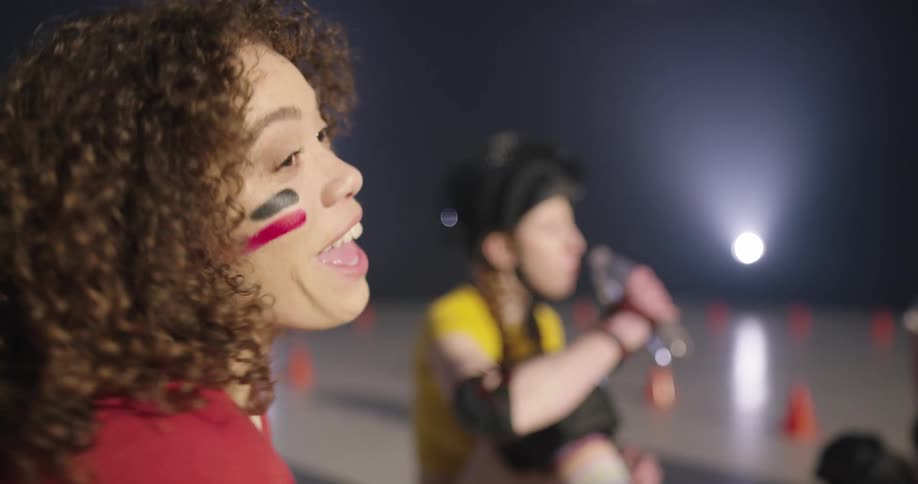 Women sitting on the ground relax and talk to each other in the roller skating rink