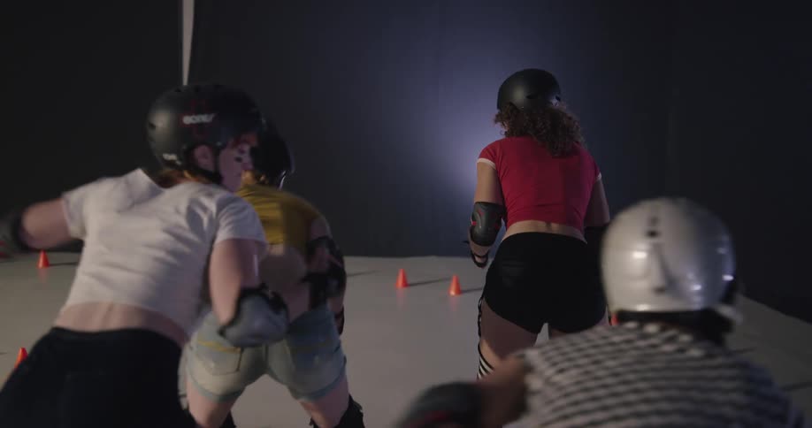 Two women on roller skates pass blockers during a competition on a small rink