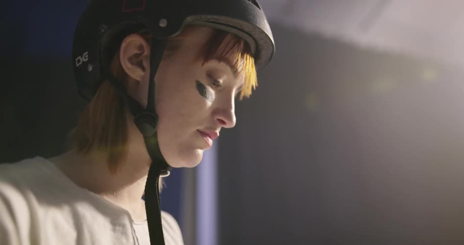 A woman wearing a helmet puts gloves on