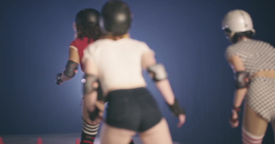 Four women on roller skates racing indoors