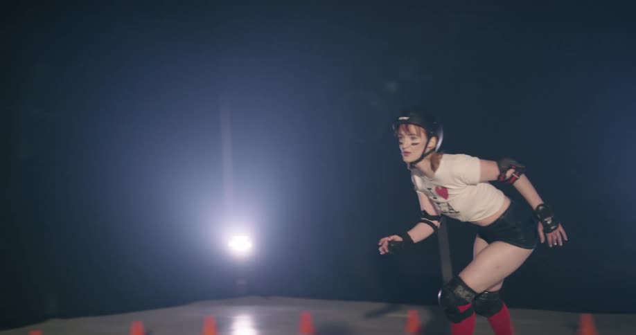 A woman with a helmet and elbow pads roller skating indoors