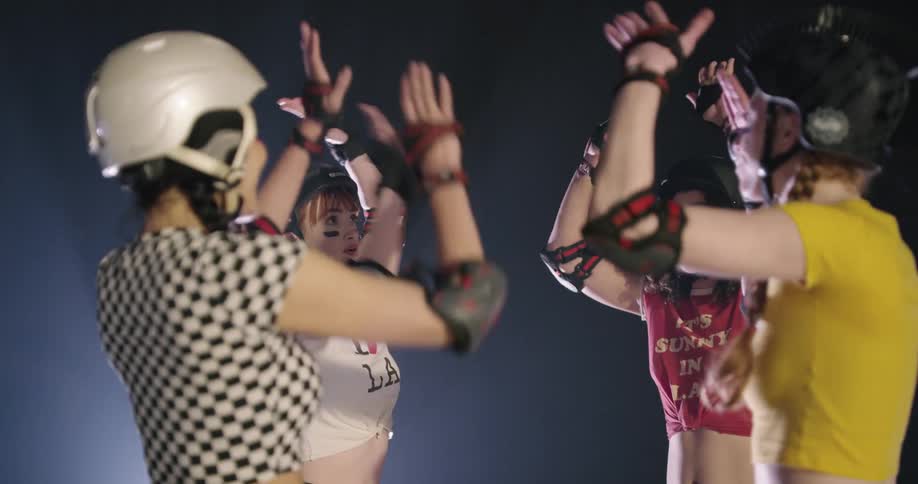Women with helmets and elbow pads standing and high fiving each other