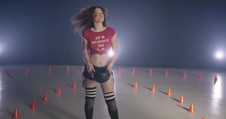 A woman standing taking off a helmet and fixing her hair
