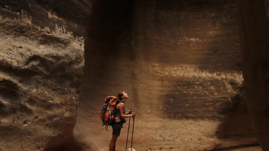 A girl is hiking through a canyon and she stops to admire the view