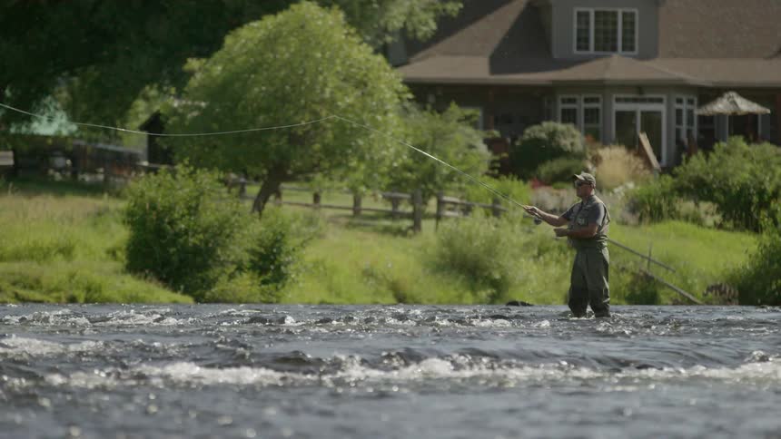 Fisherman standing in a stream casts his line