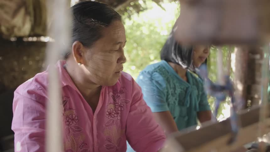 Two women sitting spinning cotton