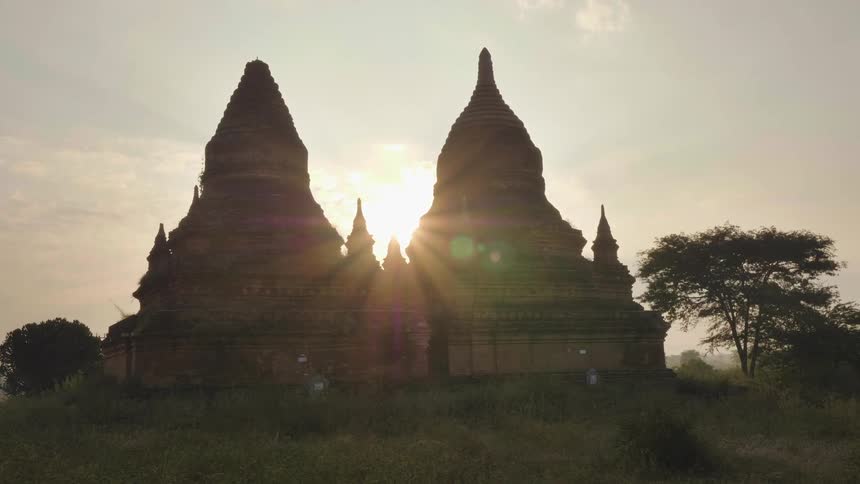 Two temples sit side by side as the sun sets behind them
