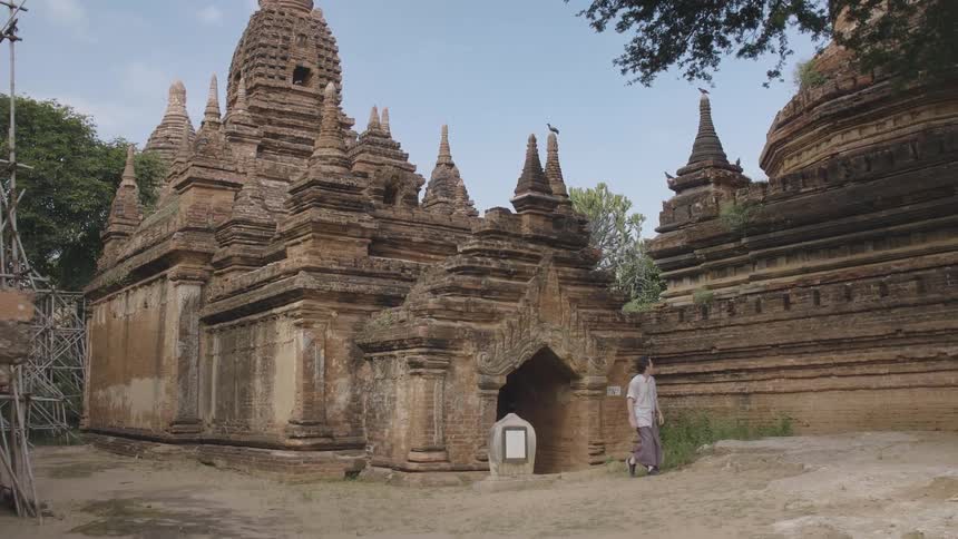 A white man strolls through an ancient temple complex