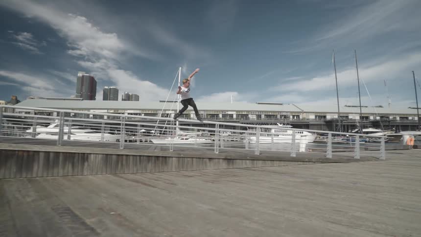 Man films skater balancing on rail near boats in the marina