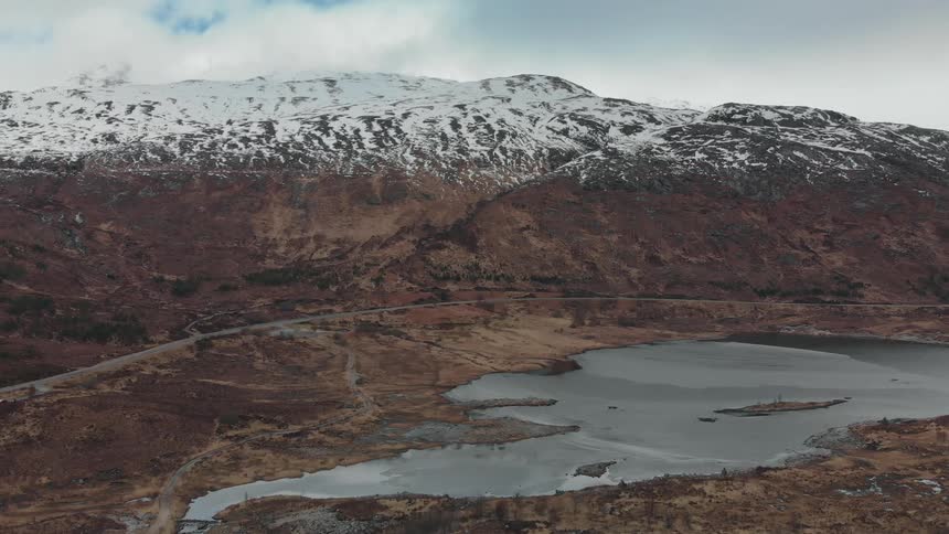 Snow covered mountain range near lake at day