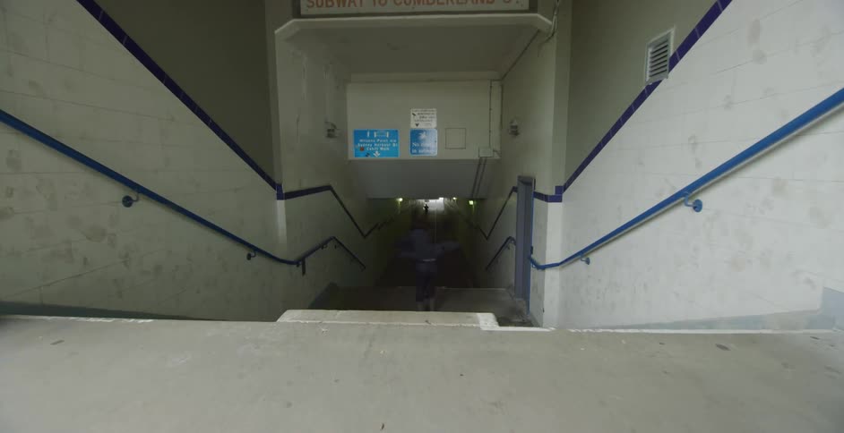 A man wearing a suit roller blade jumps down a staircase