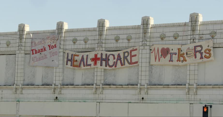 Signs thanking healthcare workers hang on a city wall