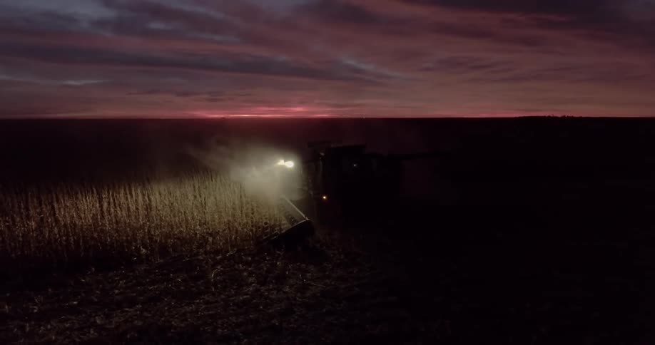 A combine plowing a field at night