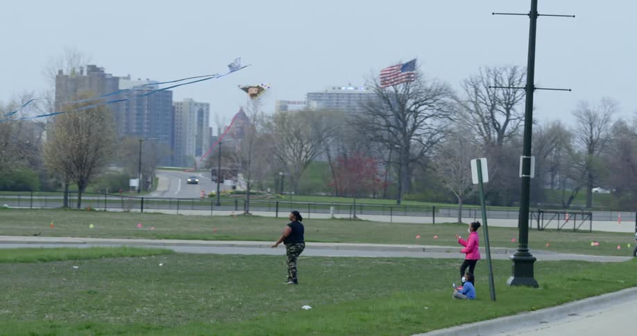 A mother and daughter fly kites at a town park