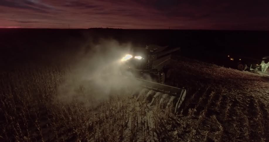 A combine works in a farm field at night