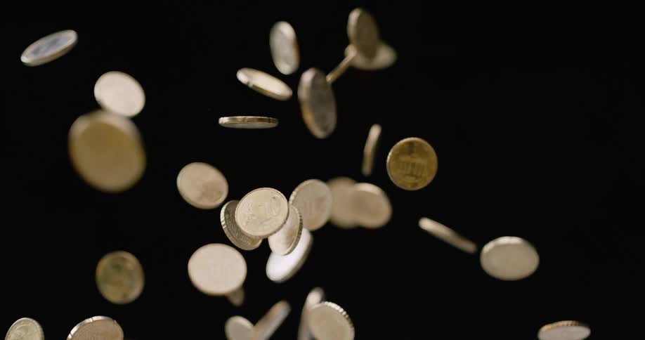 Coins being tossed up and falling down with a black background