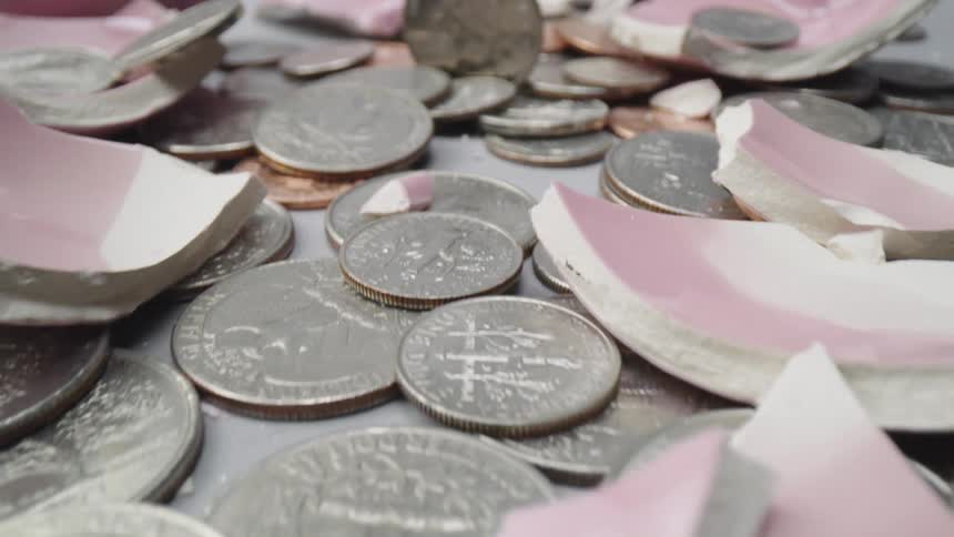 Coins scattered about along with pieces of a shattered piggy bank