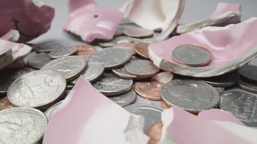 A pile of coins sits amid a broken piggy bank