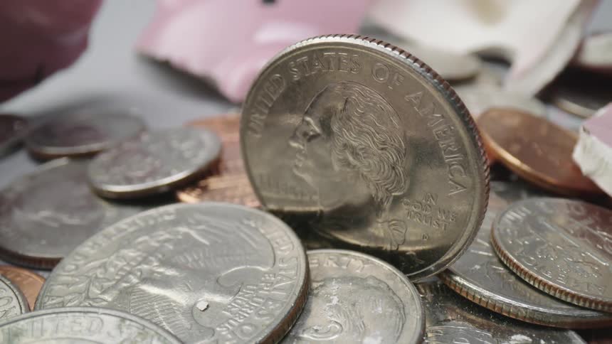A quarter stands up in a pile of currency