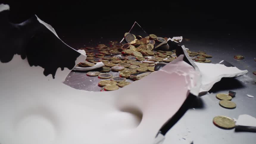 A piggy bank full of coins is smashed on a table