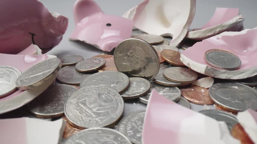 Shattered piggy bank and coins laying in a pile