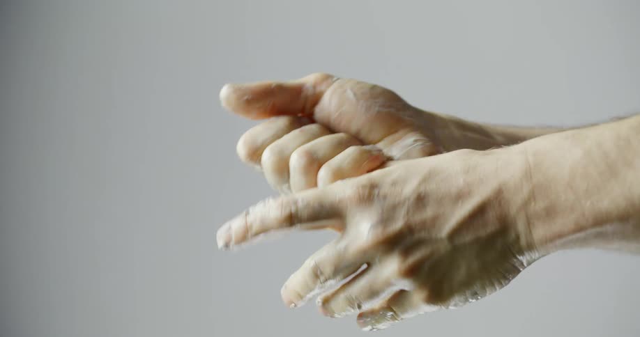 A white man scrubs his hands with soap