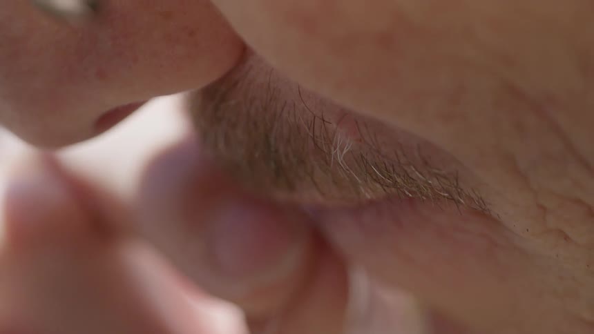 A close up of a man wetting a string in his mouth