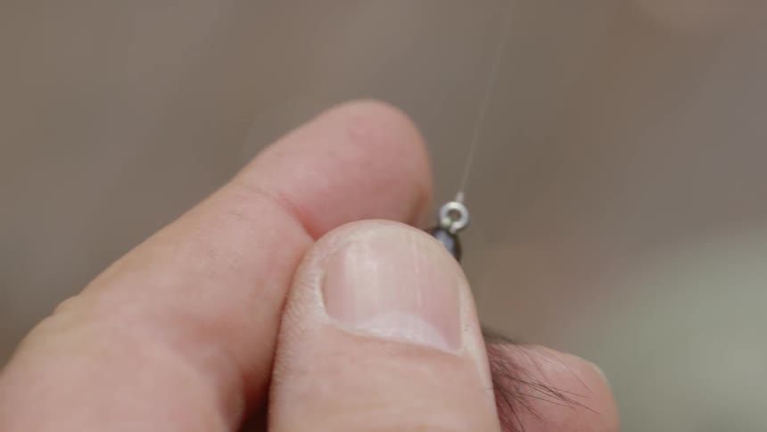 A man holding a fishing lure while pulling the line tight