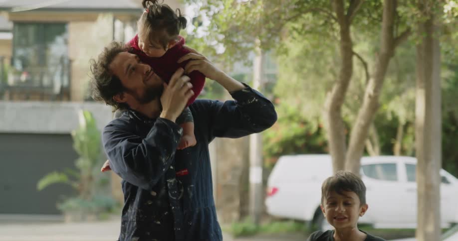 Father carries daughter as son plays with dog