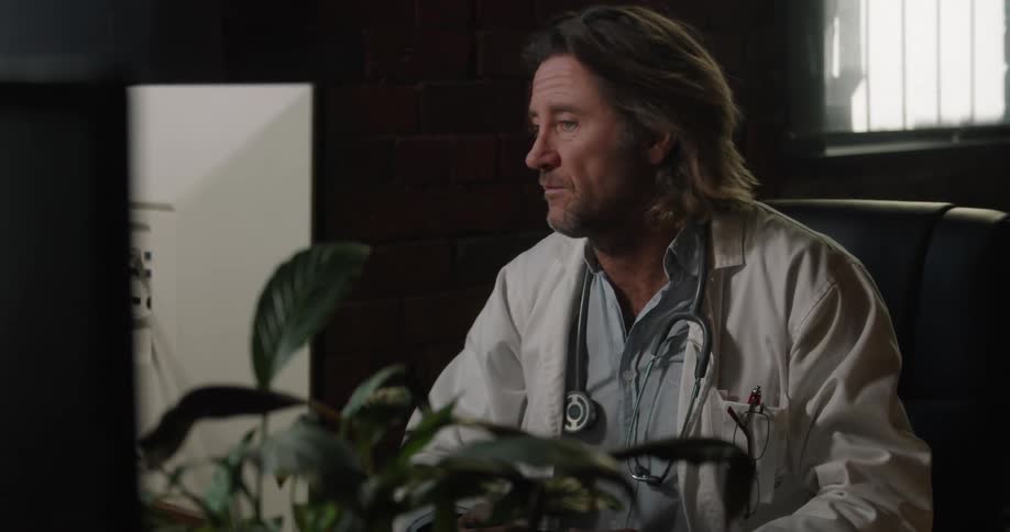 A doctor sits talking in his office