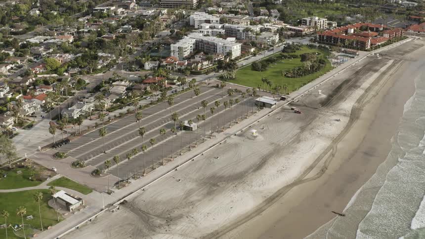 A parking lot next to a beach with houses in the background