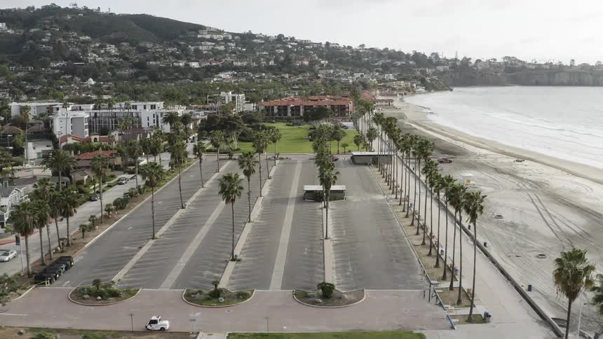 A empty parking lot sits along the shore of a coastal neighborhood