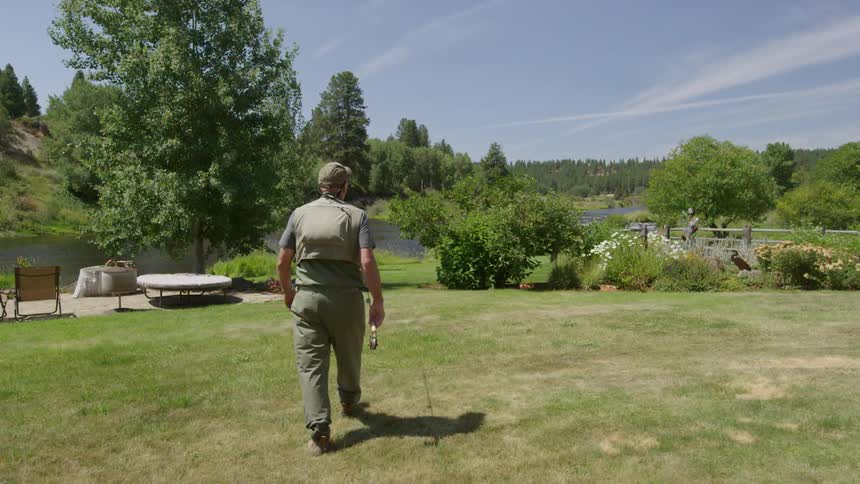 A man is walking towards the lake holding a fishing pole