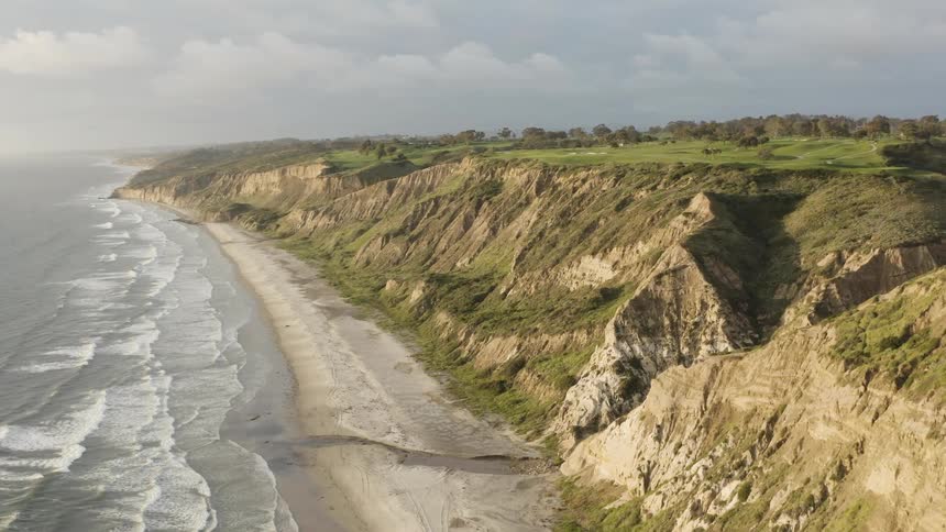 Waves roll into a a beach lined with cliffs