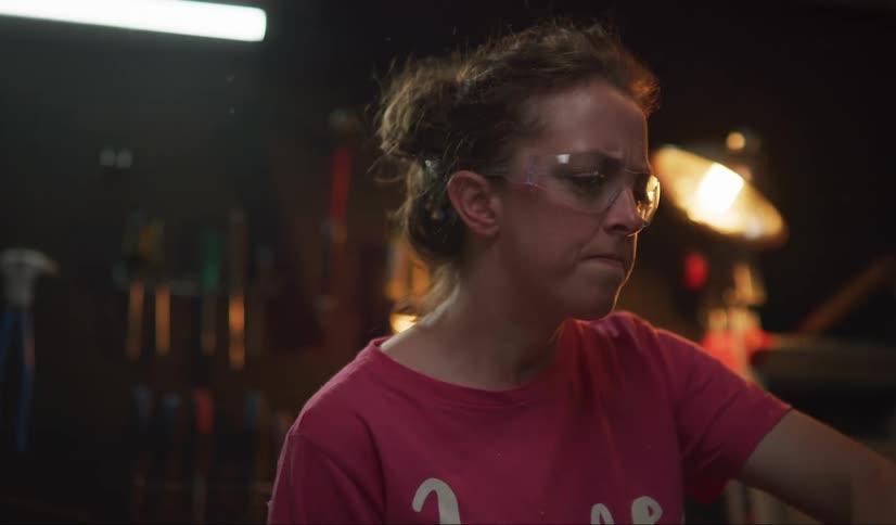 A woman cuts something just out of frame, causing a large amount of small debris to fly in the air.