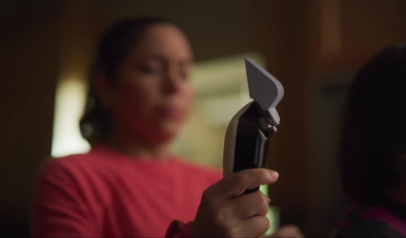 A mom jumps when she turns on the electric clippers and grimaces as she cuts her sons hair