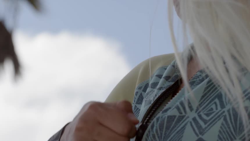 A blonde girl is zipping up her jacket