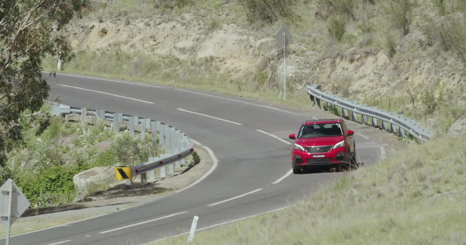 Red car drives down road in rural area