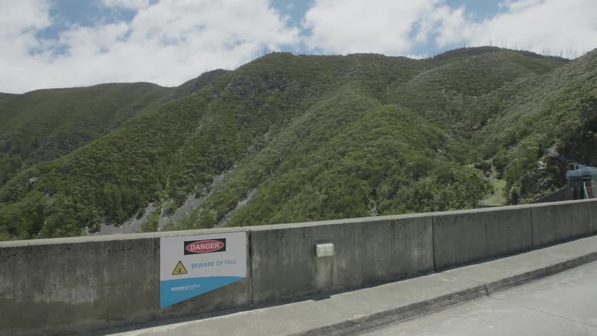 A vehicle drives across a small mountain side bridge
