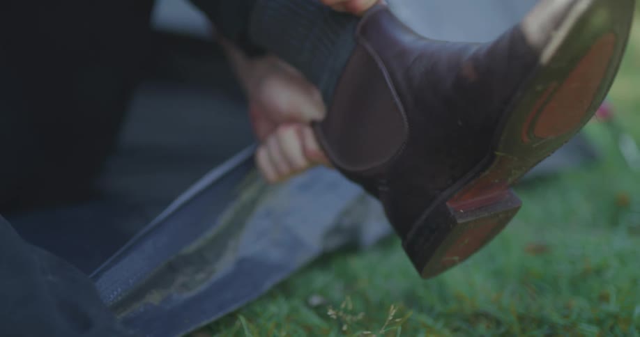 Man camping inside tent puts boot in foot