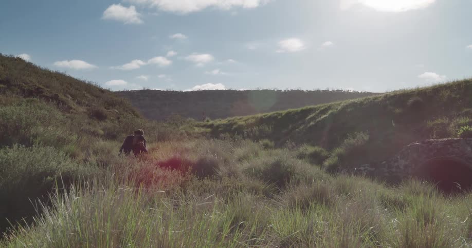 A person crouching down in the grass with a camera