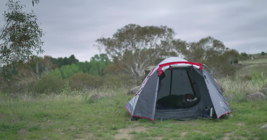 An open tent in a field on a cloudy day